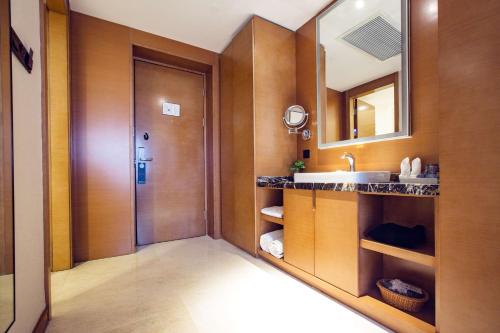 uma casa de banho com um lavatório e um espelho em Ramada Encore Wuhan em Wuhan