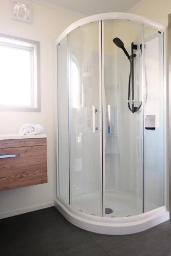 a shower with a glass enclosure in a bathroom at Tairua Shores Motel in Tairua