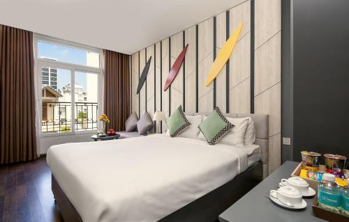 a large white bed in a room with a window at Le House Boutique Hotel - 100m to the beach in Da Nang