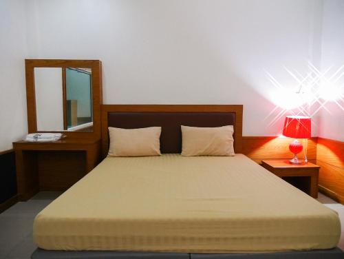 una camera da letto con un letto con specchio e lampada di Paradise Hotel a Kanchanaburi