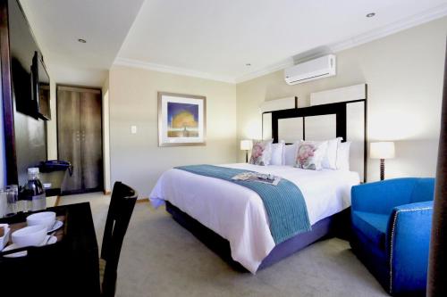 um quarto com uma cama grande e uma cadeira azul em The Clan Guest House em Maseru