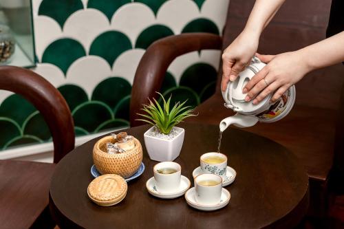a person pouring coffee into cups on a table at Le House Boutique Hotel - 100m to the beach in Da Nang