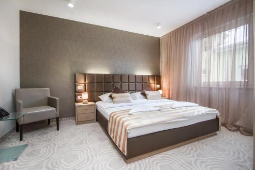 a bedroom with a large bed and a chair at Royal Airport Hotel in Velika Gorica