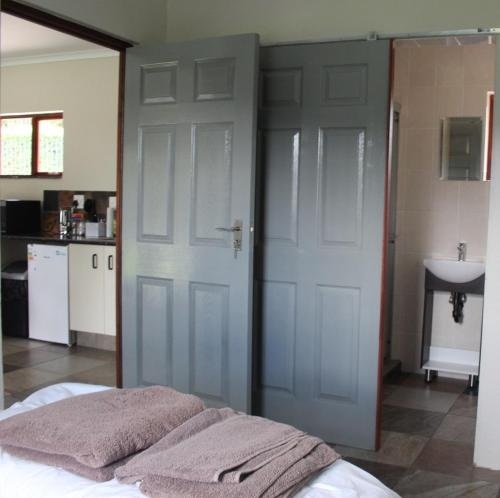 a bedroom with a bed and a door and a sink at Misty Cottage in Dullstroom