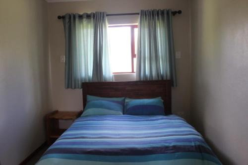 een slaapkamer met een bed en een raam met blauwe kussens bij Misty Cottage in Dullstroom
