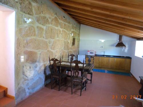 uma sala de jantar com uma parede de pedra e uma mesa e cadeiras em Casa do Forno, Viseu em Oliveira de Barreiros