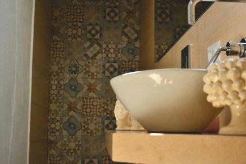 Un lavabo de baño sobre una encimera con una pared de azulejos. en Green House Beach, en Mondello
