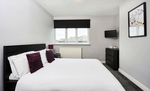 Un dormitorio con una gran cama blanca y una ventana en The Embassy Hotel, en Hull