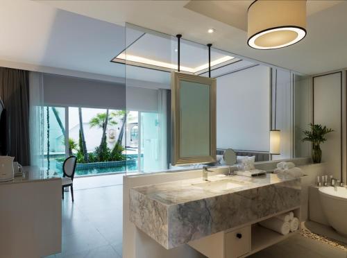 a bathroom with a large marble sink and a tub at Chanalai Romantica Resort - Adults Only, Kata Beach in Kata Beach