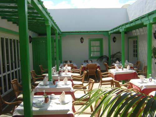 un restaurante con mesas blancas y sillas en un patio en Hotel Casa Del Embajador, en Playa Blanca