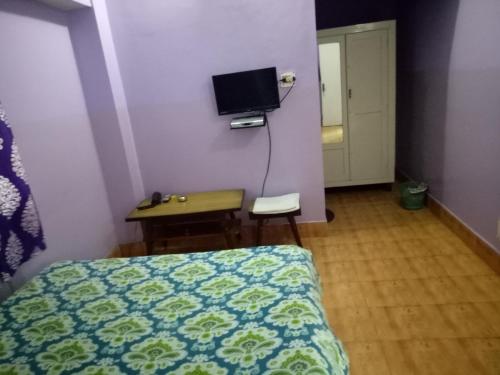 a bedroom with a bed and a desk and a tv at Hotel Kameng in Itānagar
