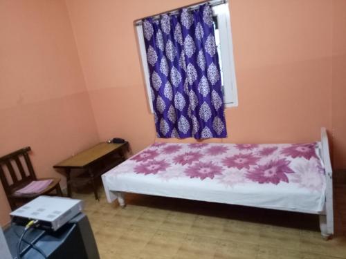a small room with a bed with a purple curtain at Hotel Kameng in Itānagar