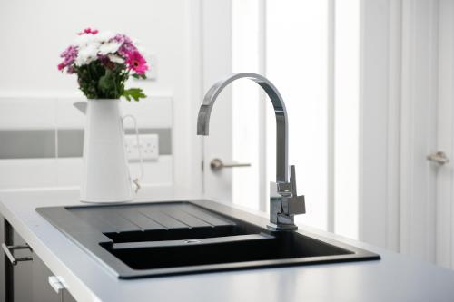 a kitchen with a sink and a vase of flowers at 'Modern Living in Old Town Stratford-upon-Avon' in Stratford-upon-Avon