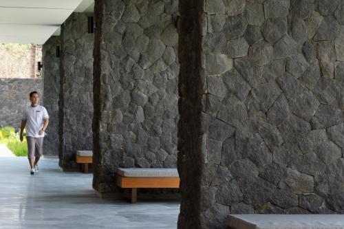 a man walking down a hallway next to a stone wall at Dialoog Banyuwangi in Banyuwangi