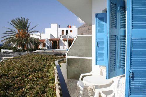 a house with a blue shutter and a table and chairs at Lefka Ori in Khóra Sfakíon