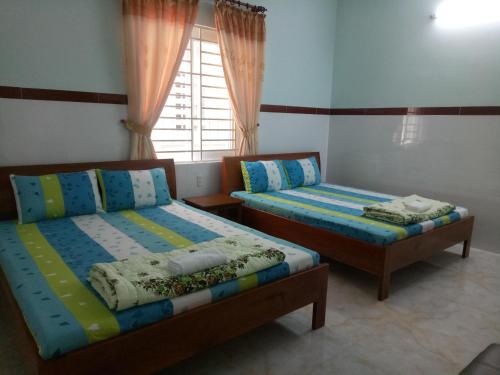 2 łóżka pojedyncze w pokoju z oknem w obiekcie Hoang Minh 846 Hostel w mieście Vung Tau