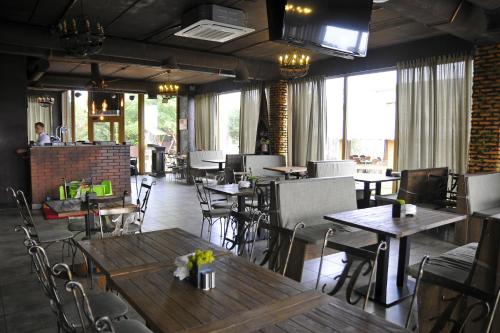 um restaurante com mesas e cadeiras de madeira e janelas em Nester House em Svityazʼ