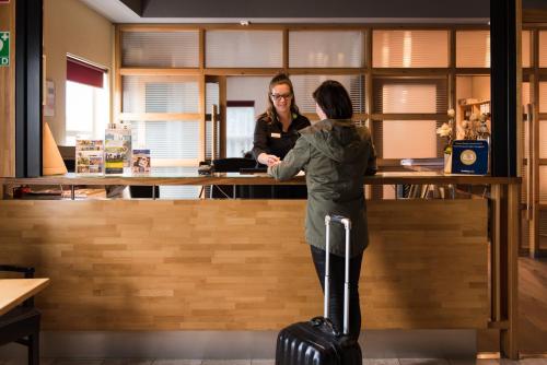 NiftrikにあるHotel Hoogeerd by Flow Niftrik - Nijmegenの二人の女性が荷物を持ってカウンターに立っている
