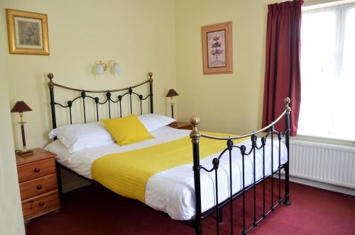 ein Schlafzimmer mit einem großen Bett und einer gelben Decke in der Unterkunft Victoria Lodge Guest House in Salisbury