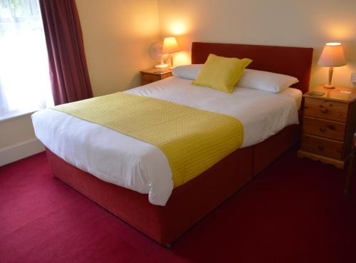 a bedroom with a large bed with a yellow blanket at Victoria Lodge Guest House in Salisbury