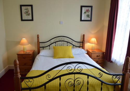 ein Schlafzimmer mit einem Bett mit einer gelben Decke und 2 Lampen in der Unterkunft Victoria Lodge Guest House in Salisbury