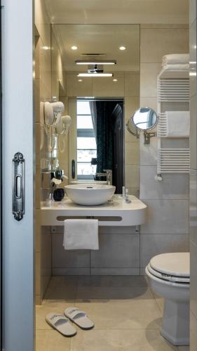 a bathroom with a sink and a toilet and a mirror at Relais Le Chevalier in Rīga