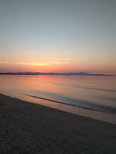 a sunset over the water on a beach at Nina Rooms (apartments) in Artemida