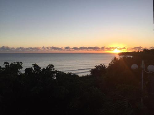 a sunset over a body of water with trees at Les Pailles en Queue - Vue mer - Appartements de Charme & Standing in Sainte-Marie