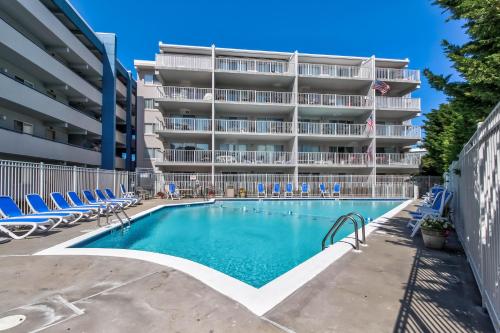 a swimming pool in front of a building with lounge chairs at Triton's Trumpet in Ocean City