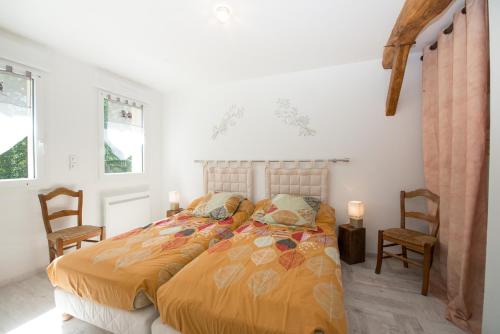 a bedroom with a bed with two chairs and two windows at Gite Des Peupliers in Girondelle