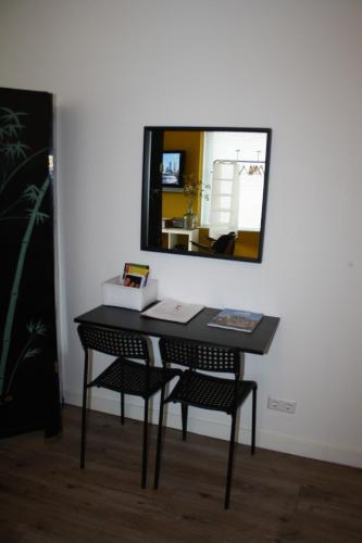 a desk with two chairs and a mirror on a wall at The Water Studio in Amsterdam
