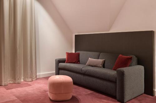 a living room with a couch and a pink stool at Zaan Hotel Amsterdam - Zaandam in Zaandam