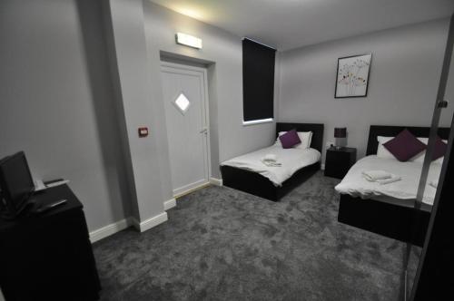 a small room with two beds and a door at The Embassy Hotel in Hull