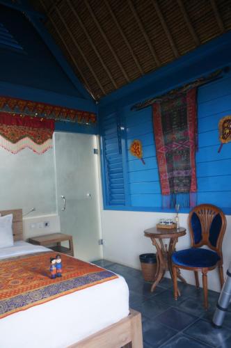 a bedroom with a bed and a table and a chair at Manggis Garden Dive Resort in Candidasa