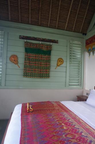 a bedroom with a bed and a window with a rug at Manggis Garden Dive Resort in Candidasa