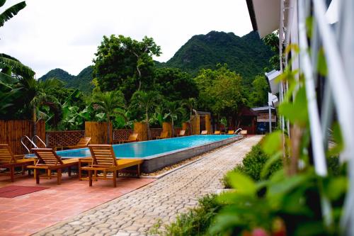 a swimming pool with chairs next to a resort at Commander Lodge in Phong Nha