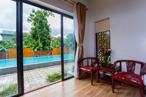 a room with a view of a pool and two chairs at Commander Lodge in Phong Nha