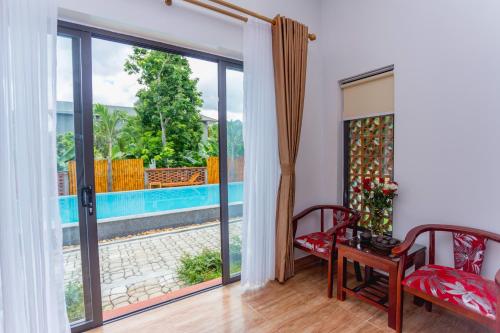 a living room with a sliding glass door with a view of a pool at Commander Lodge in Phong Nha