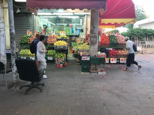 a market with people standing in front of a fruit stand at Isramax apartment near the beach. in Bat Yam