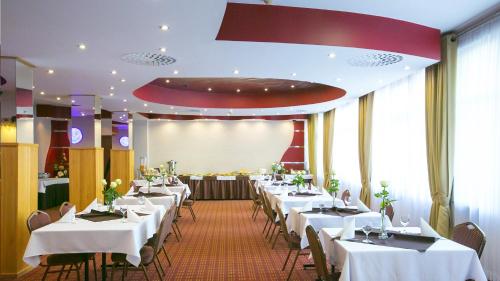 una sala da pranzo con tavoli e sedie bianchi di Hotel Unibus a Bielsk Podlaski