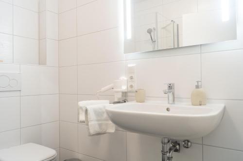 a white bathroom with a sink and a toilet at Hotel & Restaurant Sparta in Oldenburg