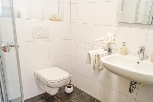 a white bathroom with a toilet and a sink at Hotel & Restaurant Sparta in Oldenburg