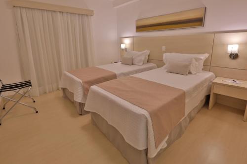 a hotel room with two beds and a table at Hotel Araucaria Flat in Araraquara