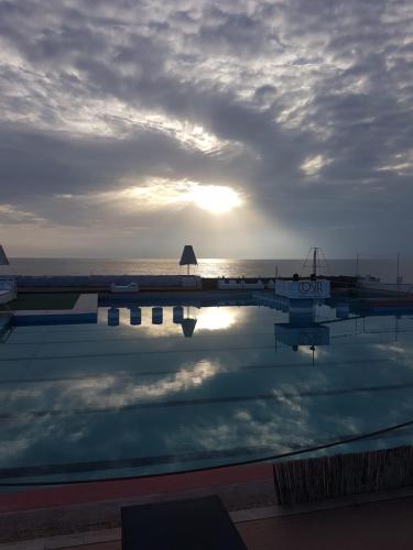 a swimming pool with the sun reflecting in the water at Le Coin Vert in Fregene