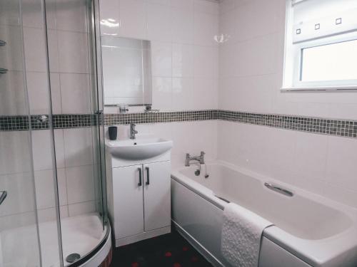 W łazience znajduje się umywalka, wanna i prysznic. w obiekcie The Mouries Holiday Cottage w mieście Fochabers