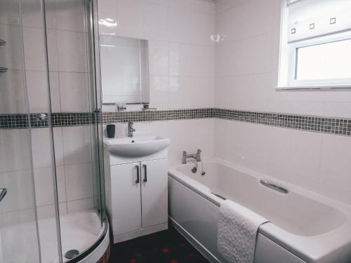 a bathroom with a sink and a tub and a shower at The Mouries Holiday Cottage in Fochabers
