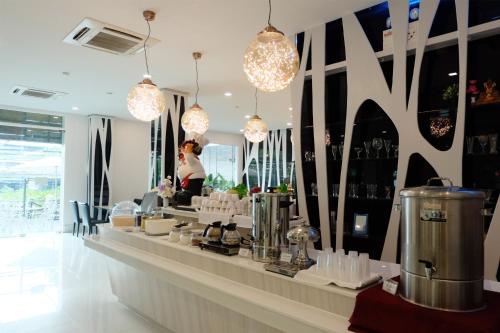 un ristorante con bancone e lampadari a braccio di Grand Hill Resort and Spa a Nakhon Sawan