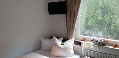 a room with a bed with a window and a pillow at Hotel Elfenmühle in Bad Bertrich