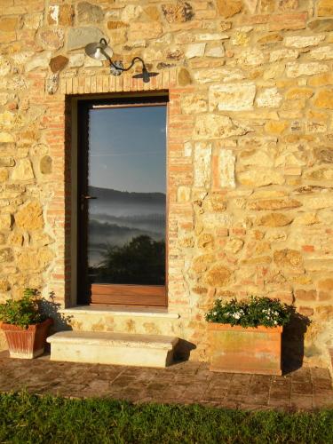 a window in a stone wall with two plants at Agriturismo Tenuta il Tasso in Rapolano Terme