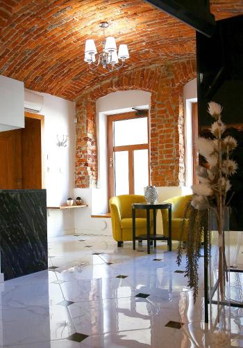 a living room with a yellow couch and a brick wall at Aparthotel Zakątna B&B in Tarnów